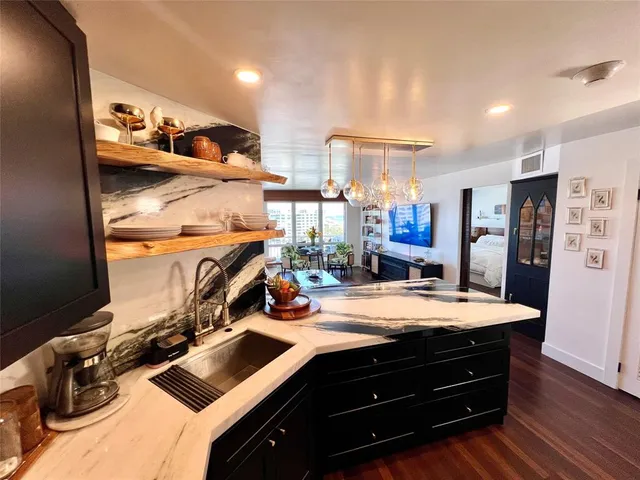 a room with stainless steel appliances kitchen island granite countertop a sink stove and refrigerator