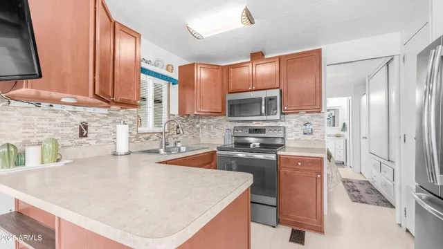 a kitchen with stainless steel appliances a sink a stove a refrigerator cabinets and a counter top space