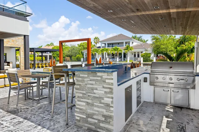 a kitchen with stainless steel appliances granite countertop a stove a sink dishwasher and chairs with wooden floor