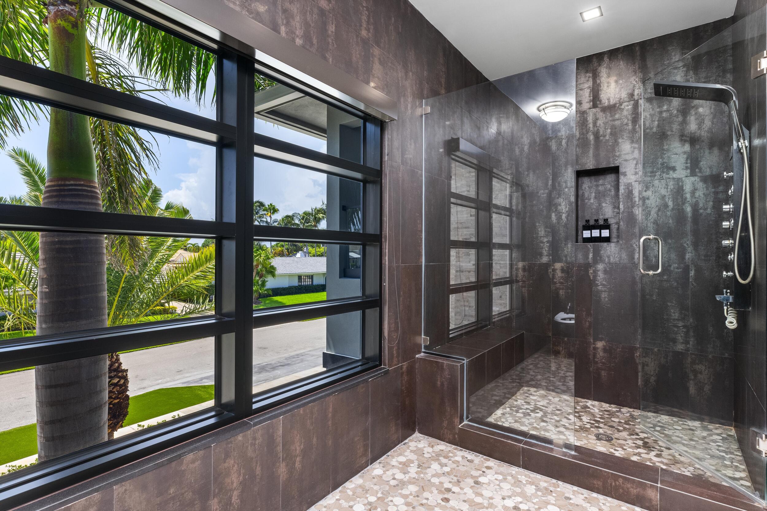 839 Northeast Bay Isle Drive Boca Raton, FL 33487 - Photo 63 of 103 a bathroom with a glass shower door and a window