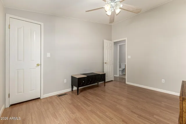 an empty room with wooden floor and a ceiling fan
