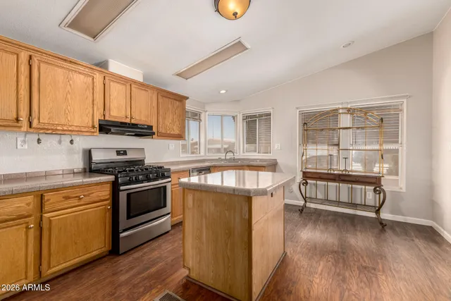 a kitchen with stainless steel appliances granite countertop a stove a sink and a refrigerator with wooden floors