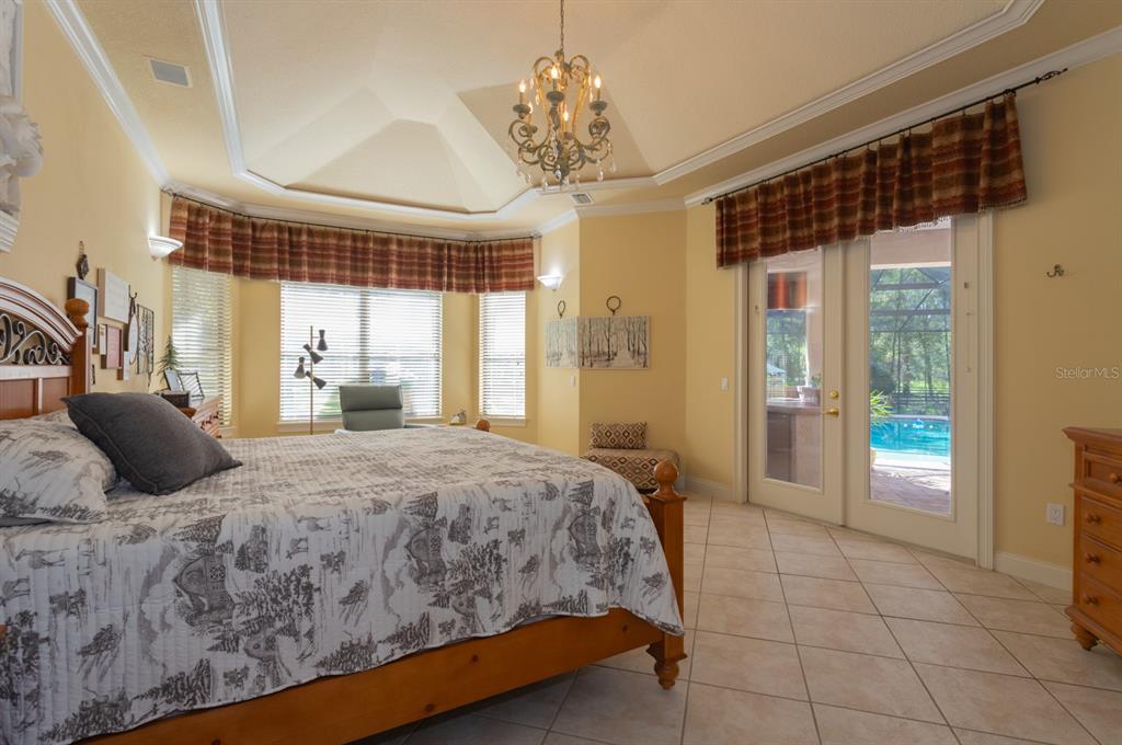 1640 Southeast 91st Place Ocala, FL 34480 - Photo 22 of 66 a bedroom with a large bed and a chandelier