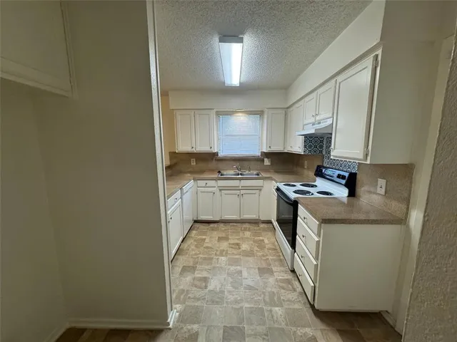 a kitchen with a sink a stove top oven and cabinetry