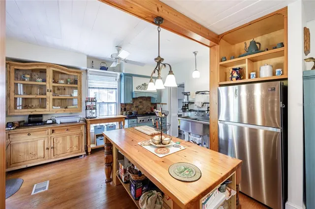 a kitchen with stainless steel appliances granite countertop a refrigerator a stove and a wooden floors