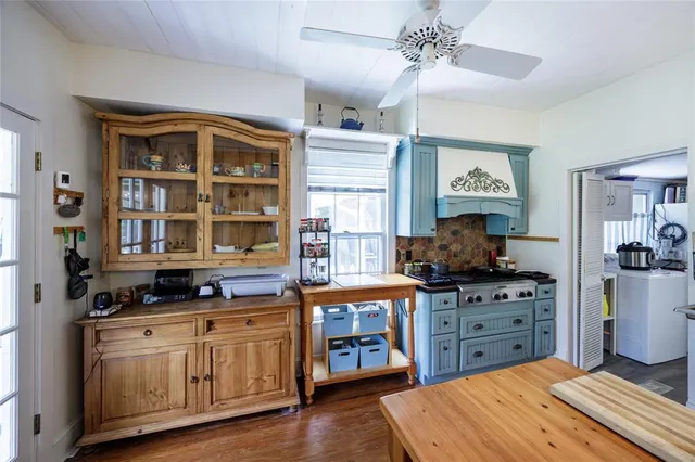 a kitchen with stainless steel appliances a stove a chimney a sink and wooden floor