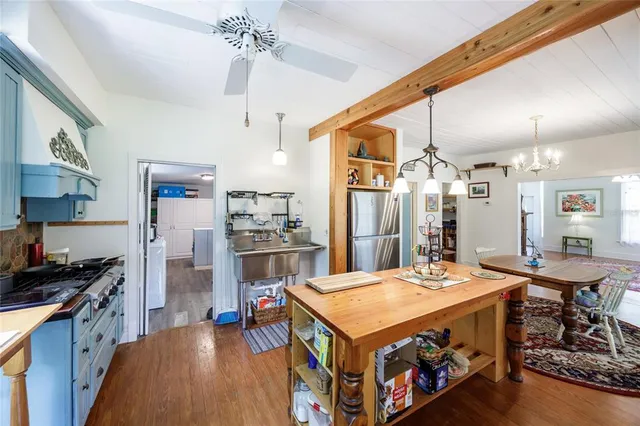 a kitchen with stainless steel appliances kitchen island a table chairs in it and wooden floors