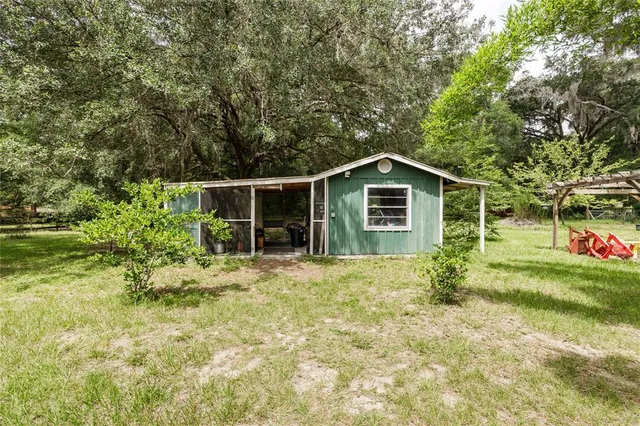 an aerial view of residential house with outdoor space and trees all around