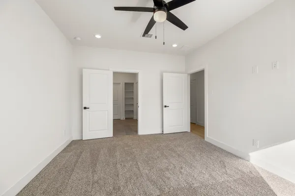 an empty room with closet and a ceiling fan