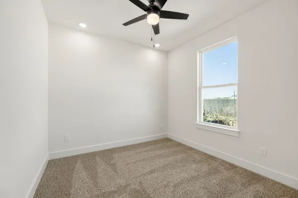 an empty room with a window and a fan
