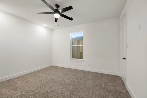 an empty room with a window and a fan