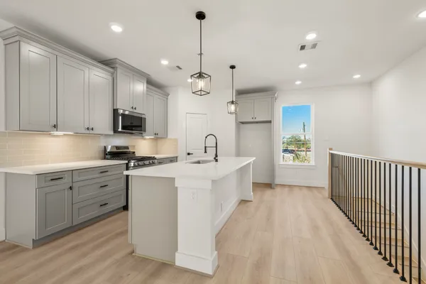 a large white kitchen with lots of counter space a sink appliances and cabinets