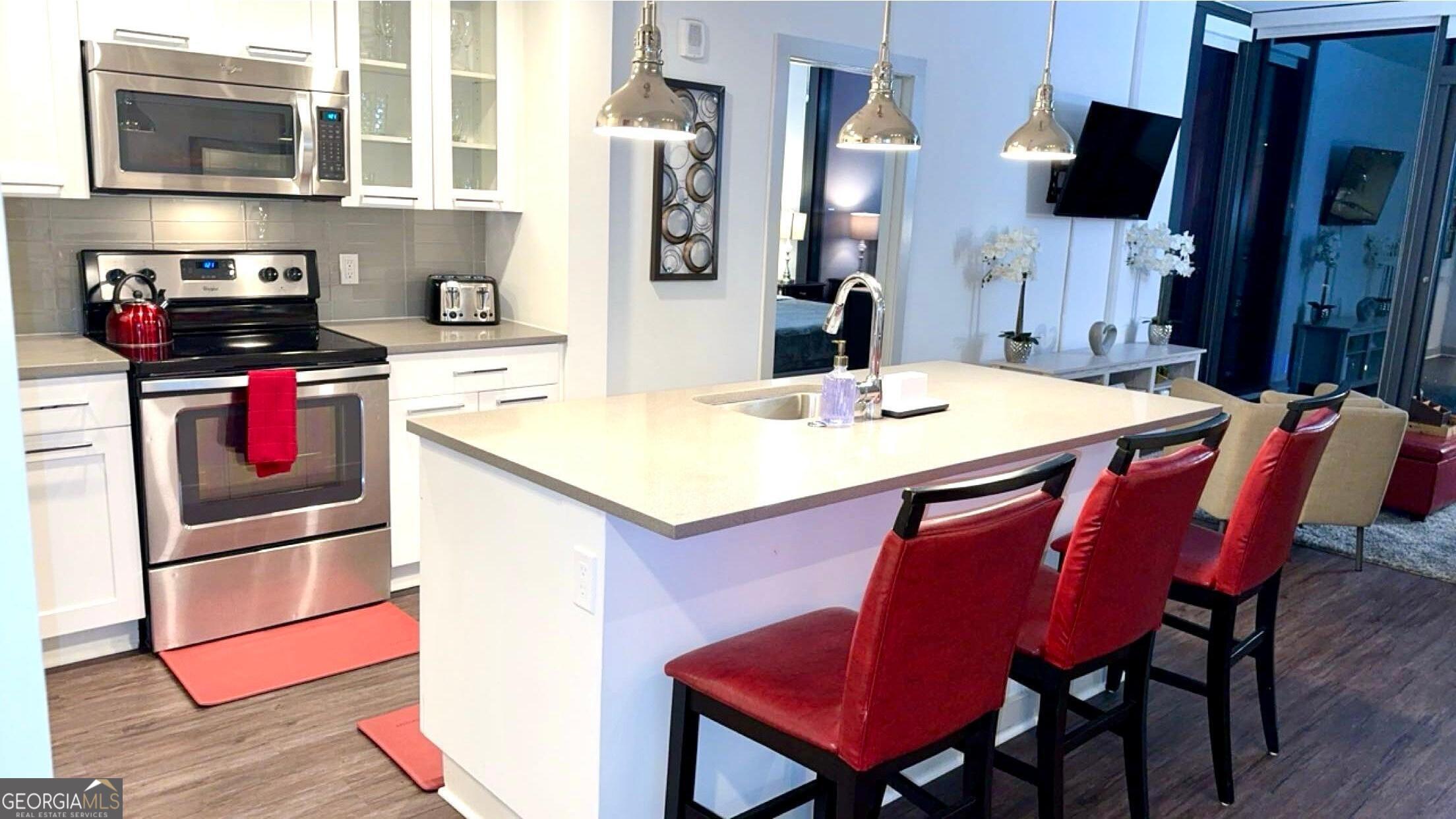 3382 Peachtree Road, Unit S12 Atlanta, GA 30326 - Photo 11 of 47 a kitchen with stainless steel appliances kitchen island granite countertop a stove a refrigerator and a dining table with wooden floor