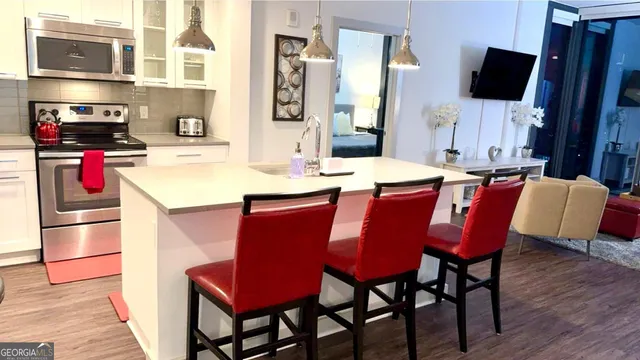 a kitchen with stainless steel appliances kitchen island granite countertop a table chairs microwave and sink