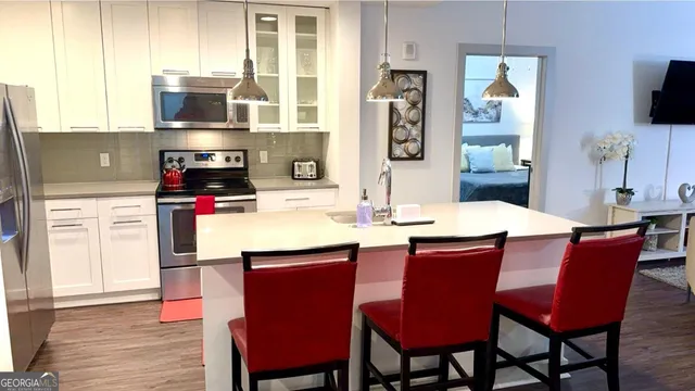 a kitchen with stainless steel appliances a dining table chairs and a refrigerator
