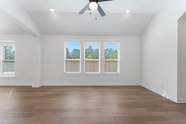 an empty room with wooden floor and windows
