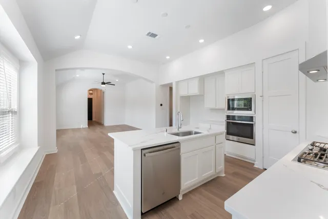 a kitchen with white cabinets and wooden floor