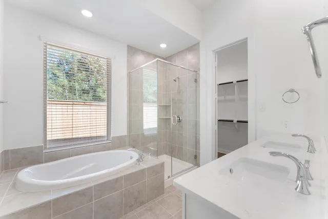 a spacious bathroom with a bathtub double sink shower and mirror