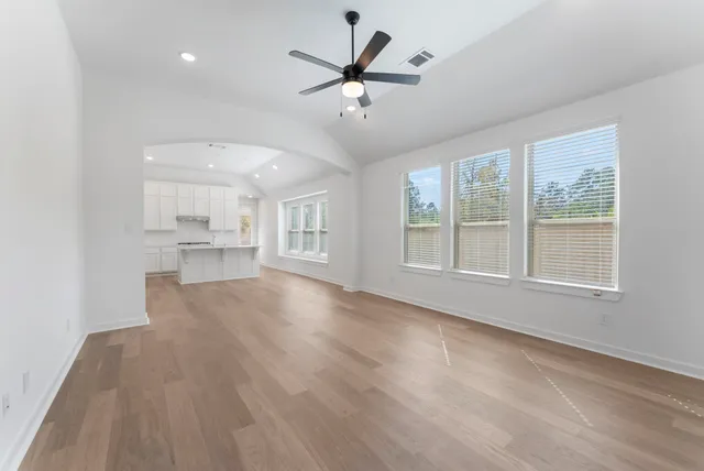 a view of an empty room with a window and wooden floor