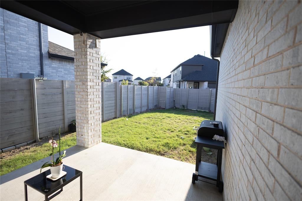 3017 Andorra Road McKinney, TX 75071 - Photo 40 of 40 Covered patio with a concrete slab, featuring a light-colored brick column and an expansive grass area
