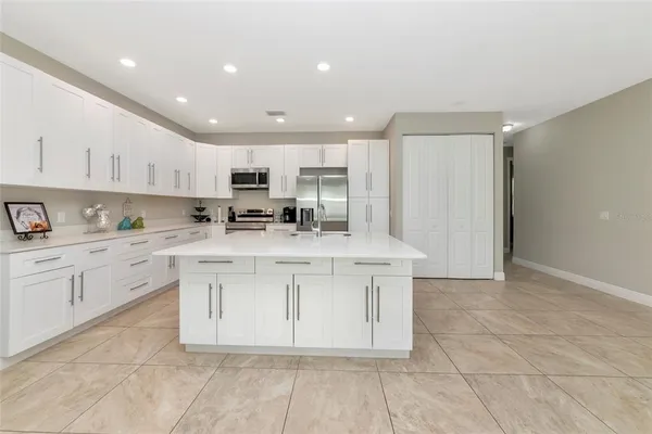 a kitchen with stainless steel appliances granite countertop a sink a stove a refrigerator and white cabinets