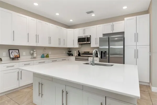a kitchen with kitchen island a refrigerator sink and white cabinets