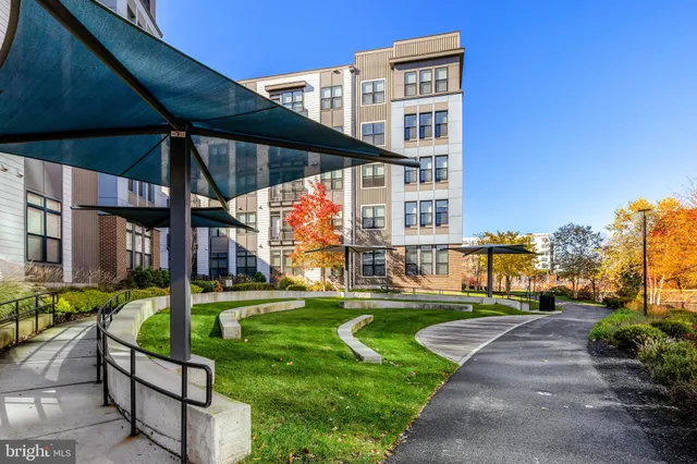 a front view of a building with glass windows and plants