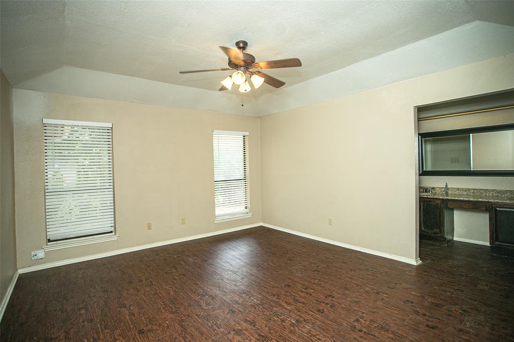 2019 West Nathan Lowe Road Arlington, TX 76017 - Photo 5 of 21 Living area featuring dark wood-finish flooring, a brick-surround fireplace with a wood mantle, and a vaulted ceiling with exposed wood beams