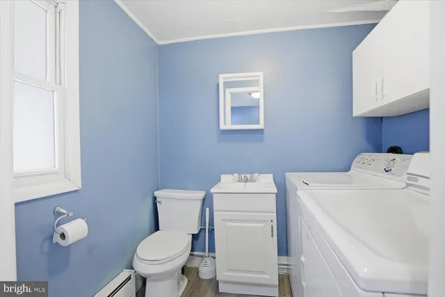a view of a hallway with wooden floor and a bathroom