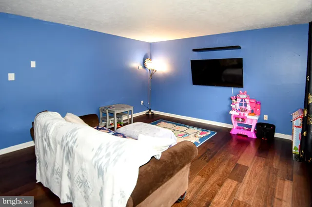 a bed sitting in a bedroom next to a flat screen tv and a wooden floor