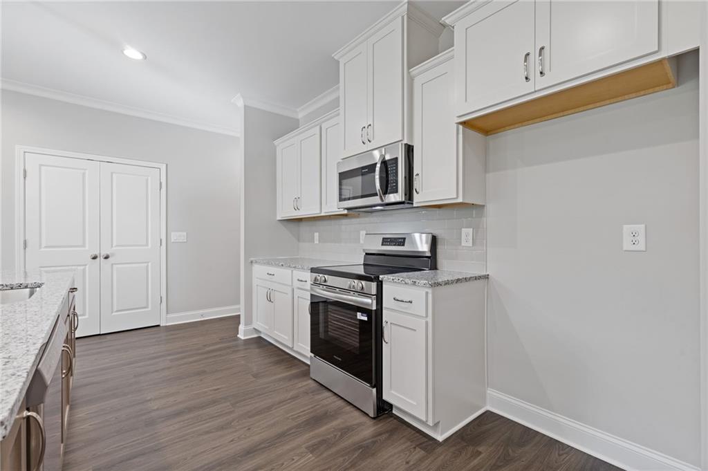 2717 Rylee Carter Street Dacula, GA 30019 - Photo 9 of 29 a kitchen with stainless steel appliances granite countertop a stove a sink and a microwave