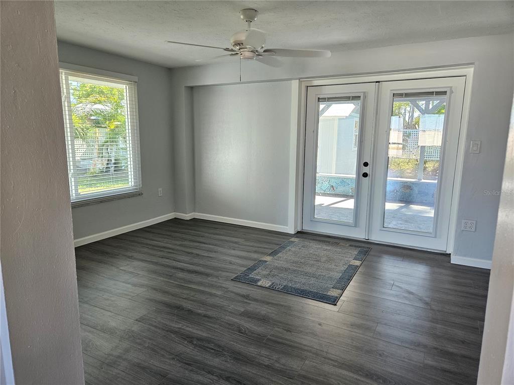8229 Cypress Road Englewood, FL 34224 - Photo 15 of 44 an empty room with wooden floor cabinet and windows