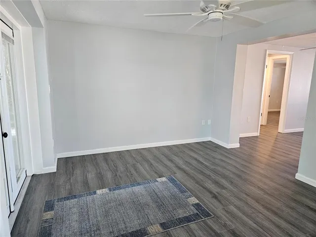 an empty room with wooden floor closet and windows