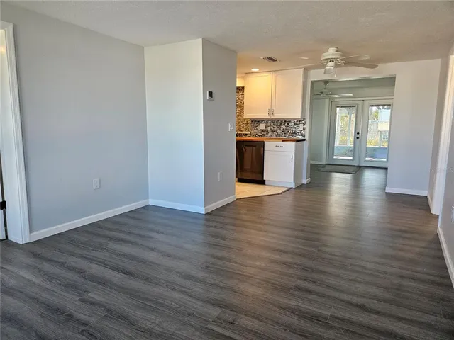 a view of a kitchen and an empty room with wooden floor