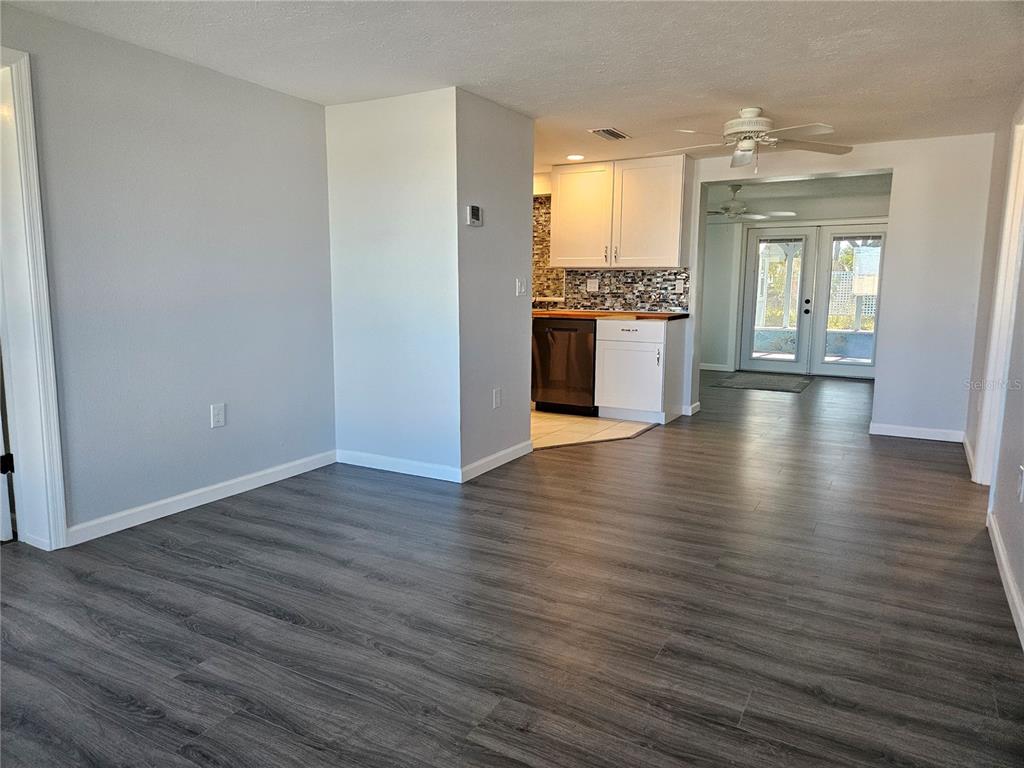 8229 Cypress Road Englewood, FL 34224 - Photo 4 of 44 a view of a kitchen and an empty room with wooden floor