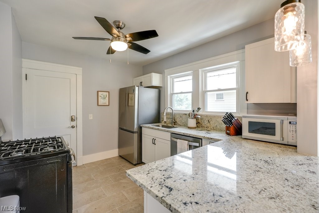 2135 Renrock Road Cleveland, OH 44118 - Photo 24 of 44 Kitchen with hanging light fixtures, ceiling fan, light stone counters, white cabinetry, and stainless steel appliances