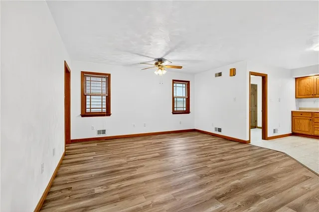 a view of an empty room with a window and wooden floor