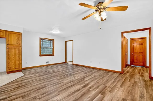 a view of an empty room with window and wooden floor