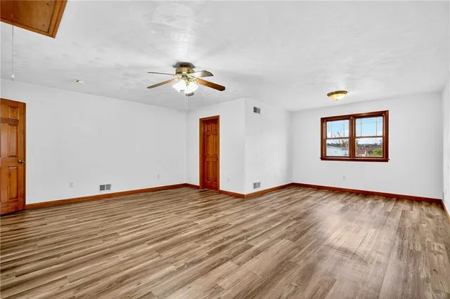 a view of an empty room with a window and wooden floor