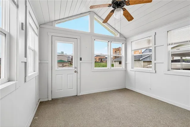an empty room with windows and chandelier fan