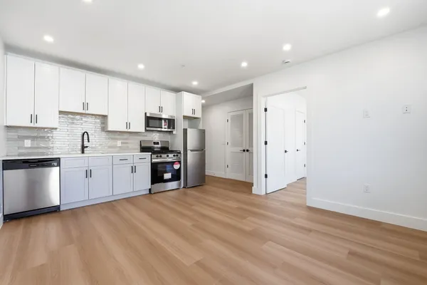 a kitchen with stainless steel appliances a refrigerator and white cabinets