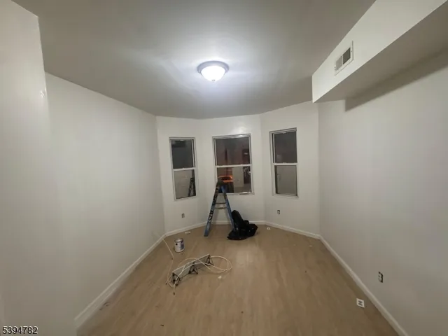 an empty room with wooden floor and a refrigerator