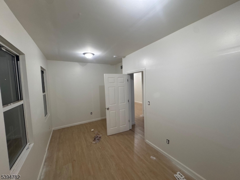 60 South 12th Street, Unit 3 Newark, NJ 07107 - Photo 4 of 9 an empty room with wooden floor and a refrigerator