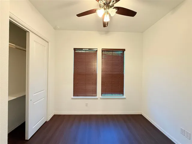 an empty room with wooden floor closet and windows