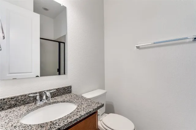 a bathroom with a granite countertop sink toilet and mirror