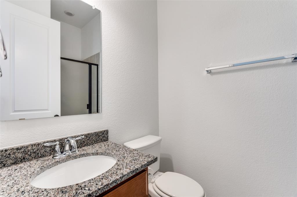 9815 Romo Street Irving, TX 75063 - Photo 13 of 25 a bathroom with a granite countertop sink toilet and mirror