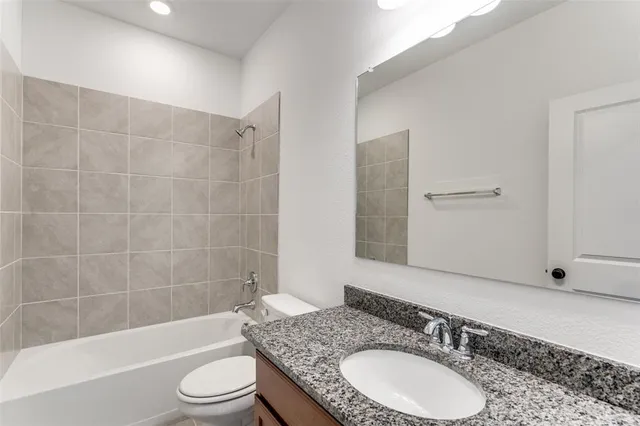 a bathroom with a granite countertop sink toilet mirror and bathtub