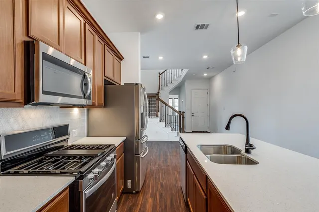 a kitchen with stainless steel appliances granite countertop a sink a stove and a wooden floor