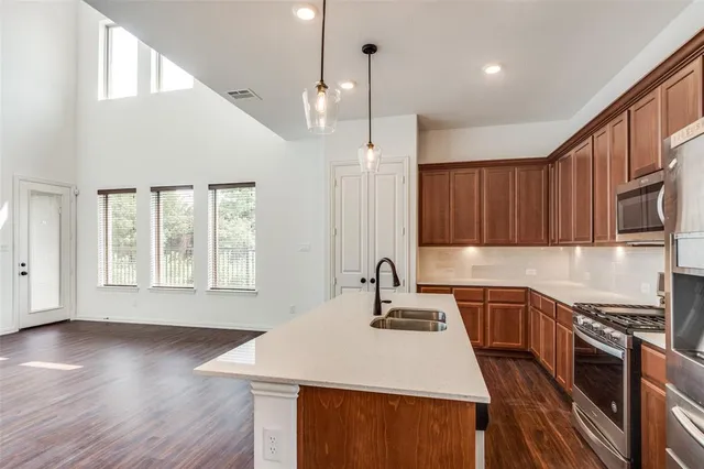 a kitchen with a sink a stove a kitchen island and chairs with wooden floor
