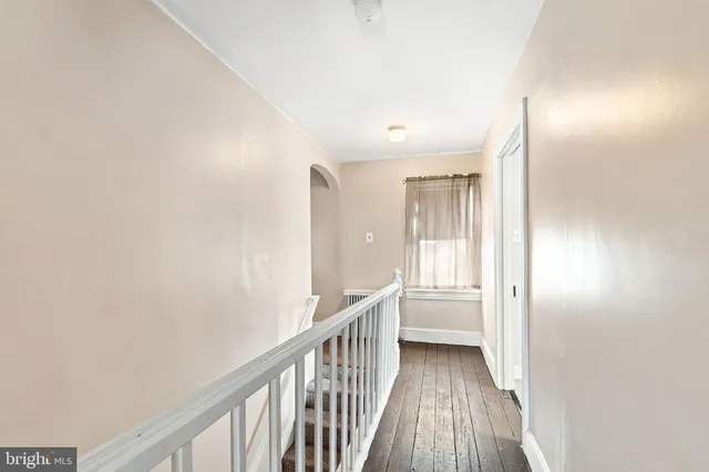 a view of a hallway with wooden floor and a bathroom